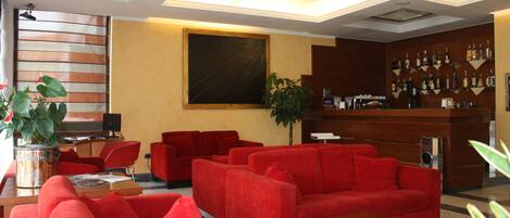 A lobby with red sofas, a wooden reception desk, and a wall-mounted liquor display.