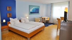 A hotel room with a large bed, a desk, a chair, a lamp, and a painting on the wall. - Hotel Am Froschbächel (Bühl)