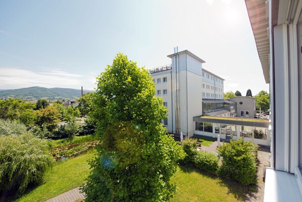 A modern building with a flat roof and large windows, surrounded by lush greenery and a clear sky. - Hotel Am Froschbächel (Bühl)
