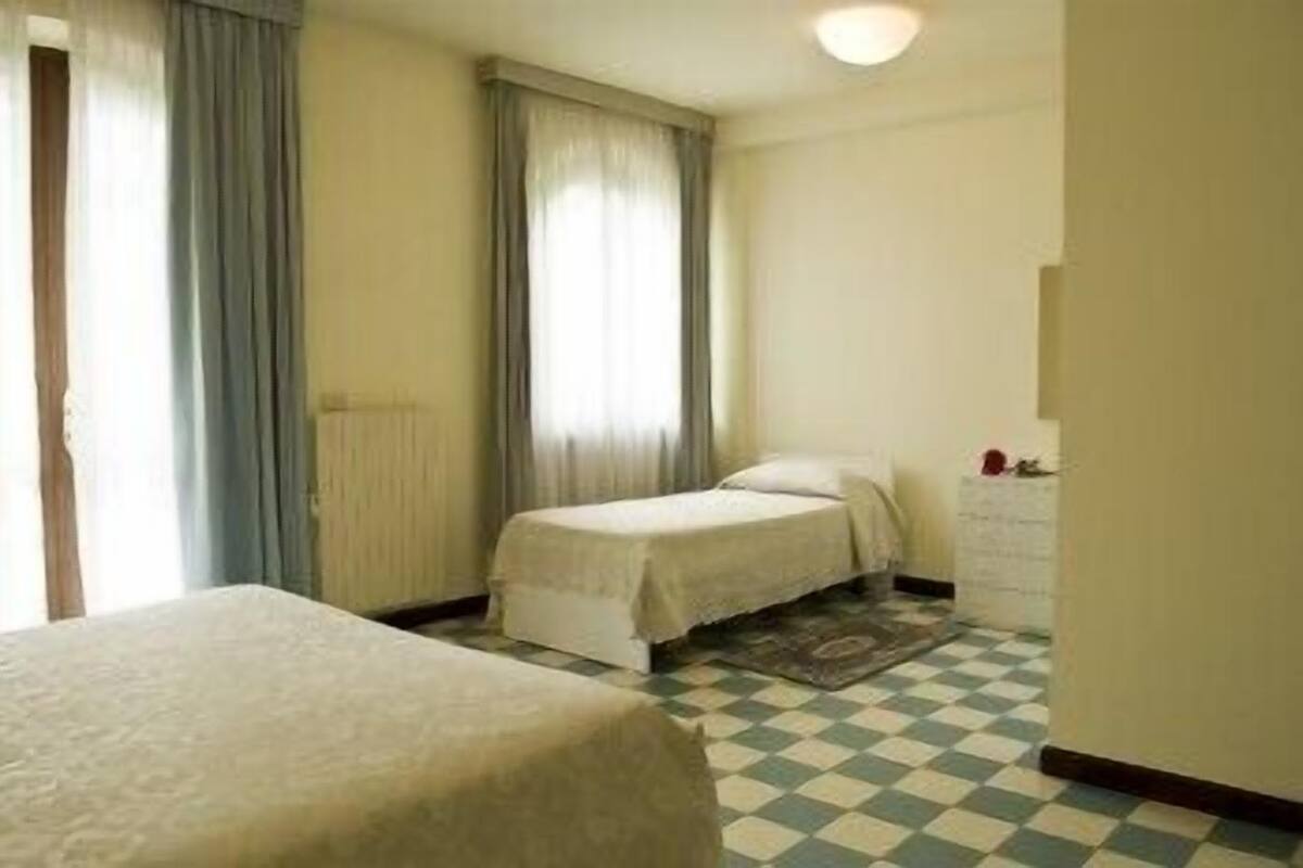 Une chambre d’hôtel avec deux lits, un sol à carreaux et une fenêtre avec des rideaux.