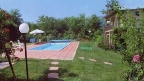 Un jardin avec une piscine, une terrasse et une maison.