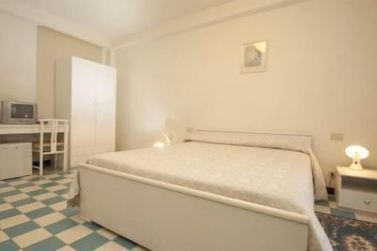 Une chambre à coucher comprenant un lit, un bureau, une chaise et une petite table avec une lampe.
