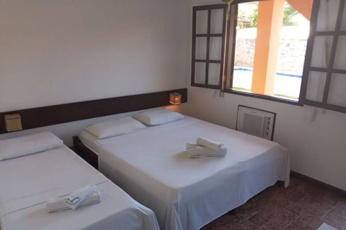 A hotel room with two single beds, a window with a view, and a heater on the wall.