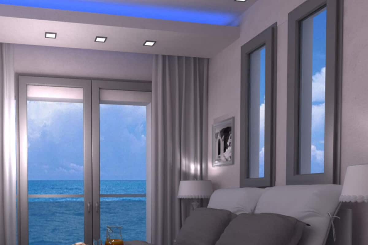 Un dormitorio moderno con cama, mesitas de noche y vista al océano.