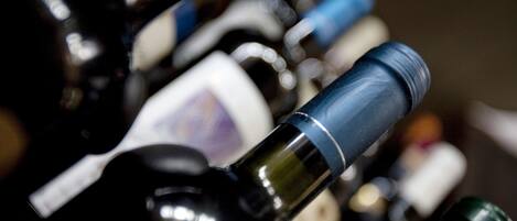 Primer plano de varias botellas de vino con etiquetas, algunas con texto visible y otras con el texto borroso.