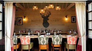 L’intérieur d’un restaurant avec un mur en bois, la silhouette d’un cerf et un coin bar avec des chaises et des bouteilles.