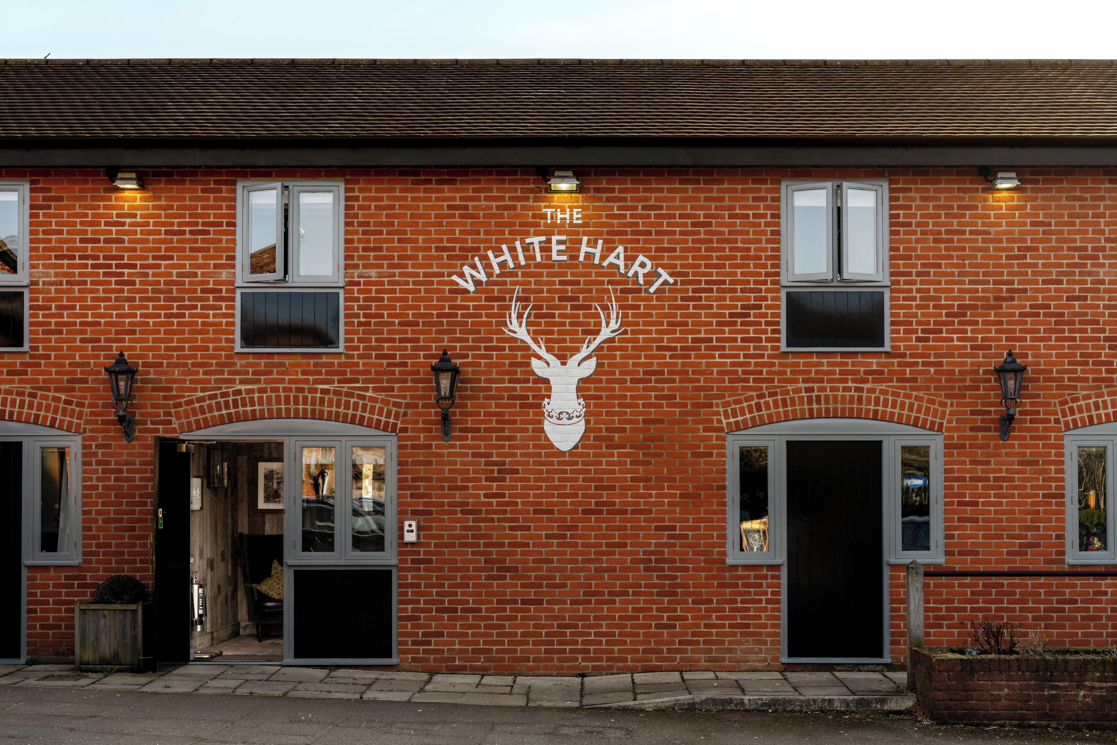 A brick building with the sign 'The White Hart' and a deer head logo.