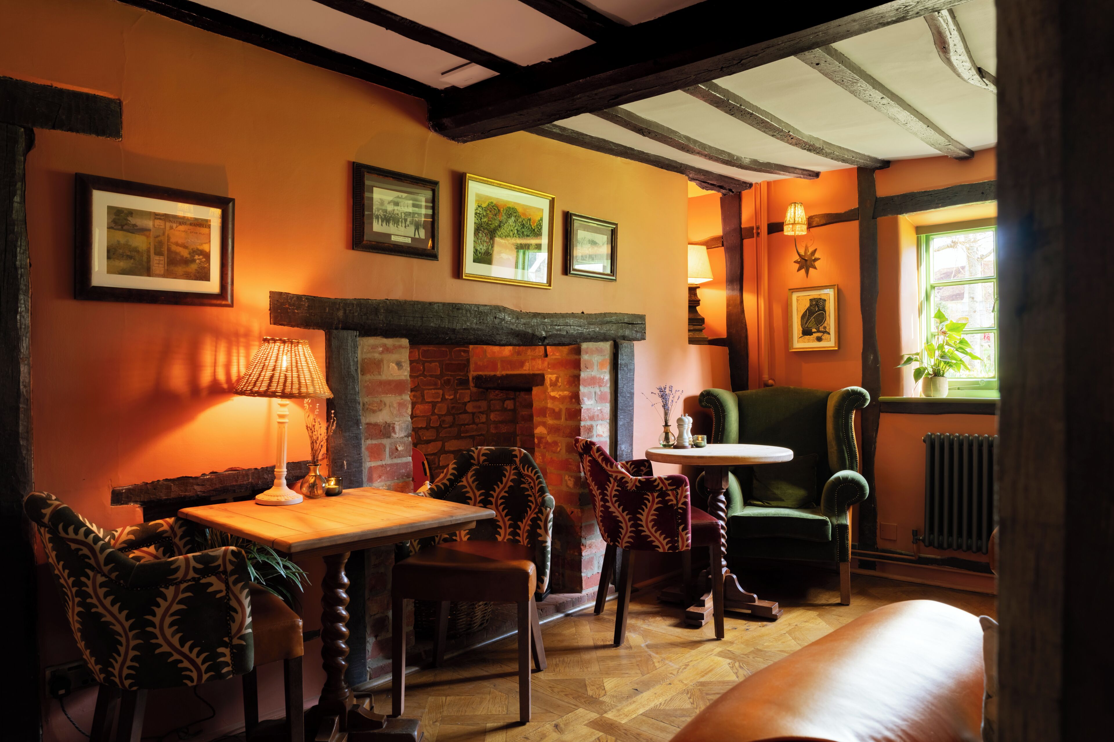 A cozy room with a fireplace, wooden furniture, and framed pictures on the wall.