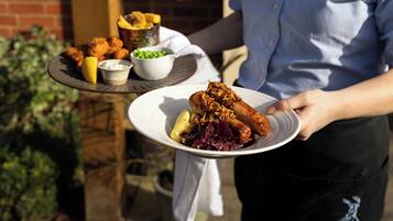 A person holding a plate with food and a bowl of peas.