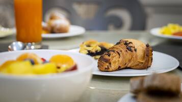 A breakfast setting with croissants, fruit, and a glass of orange juice on a table.