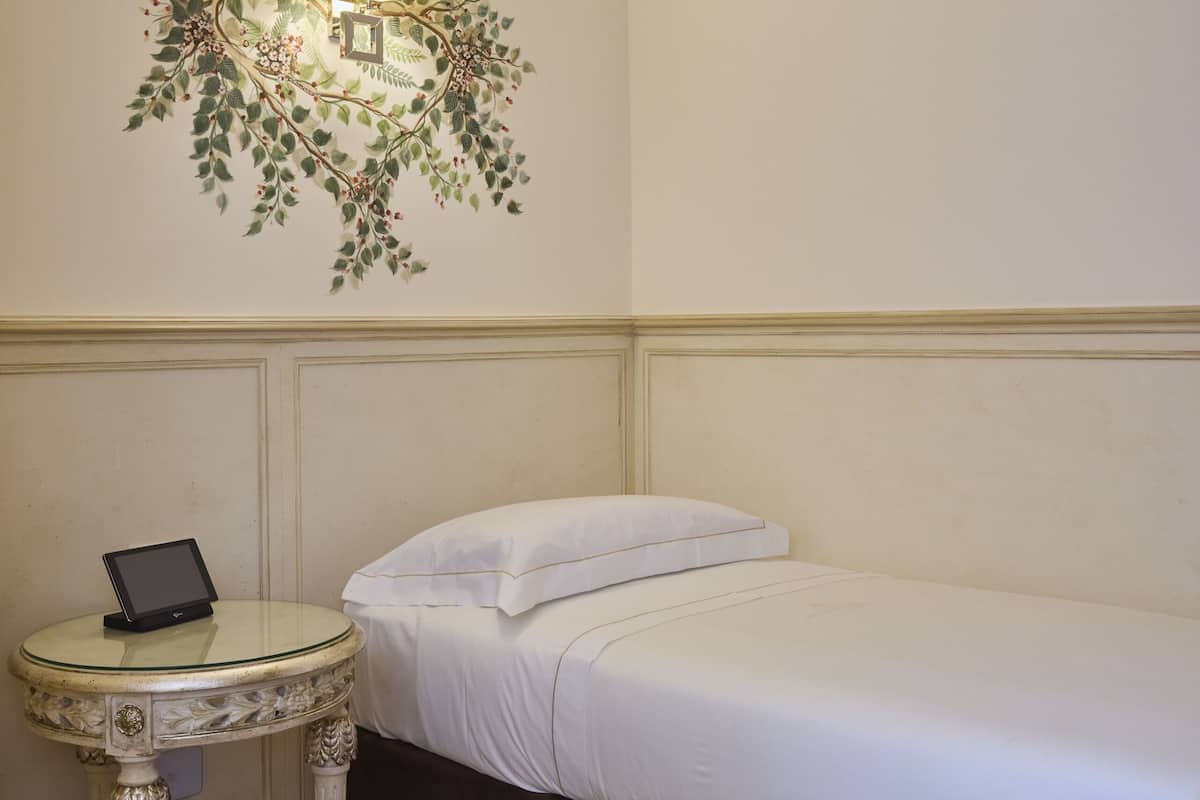 A bedroom with a bed, a bedside table with a lamp, and a wall-mounted light fixture.