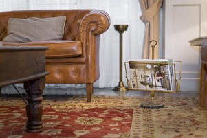Un divano in pelle marrone con un cuscino, un tappeto decorativo e un piccolo tavolino con un oggetto ornamentale.