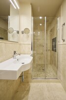 Un bagno moderno con doccia vetrata, lavandino bianco e un ampio specchio.