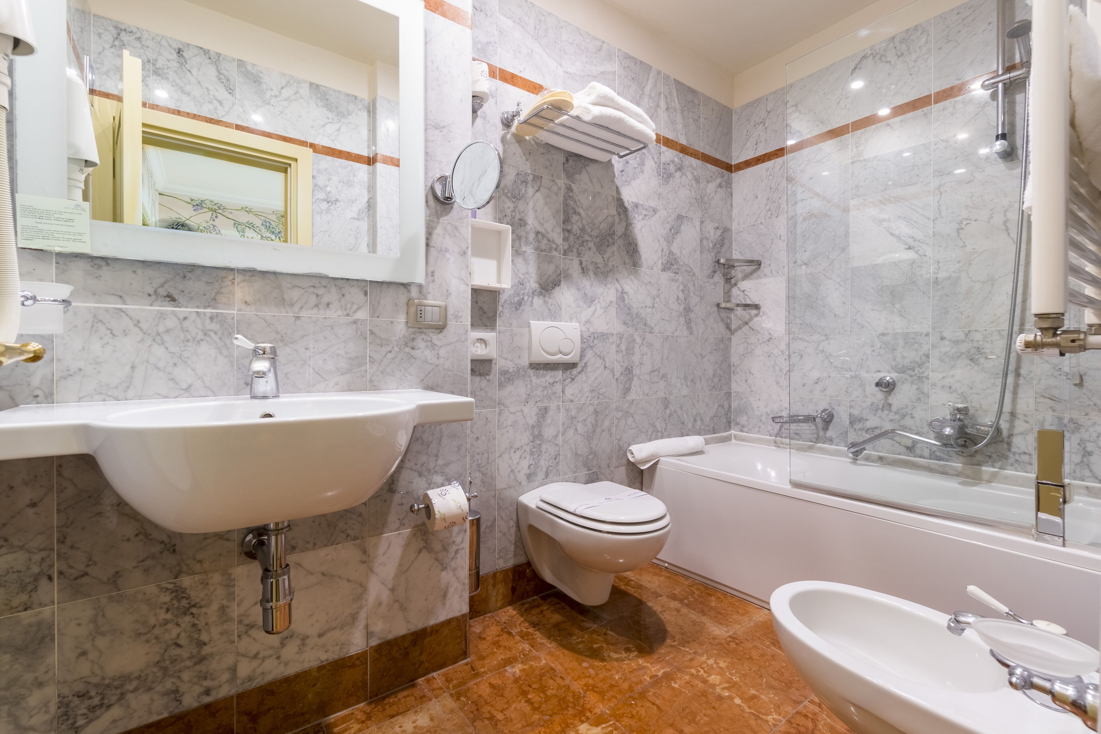 Un baño con lavabo, inodoro y bañera de mármol.