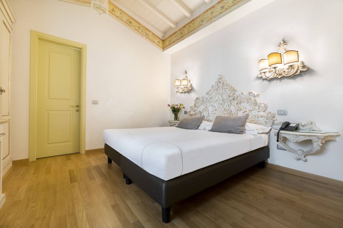 A bedroom with a bed, a nightstand, a lamp, and a door.