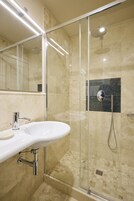 Un bagno moderno con doccia vetrata, lavandino bianco e specchio.