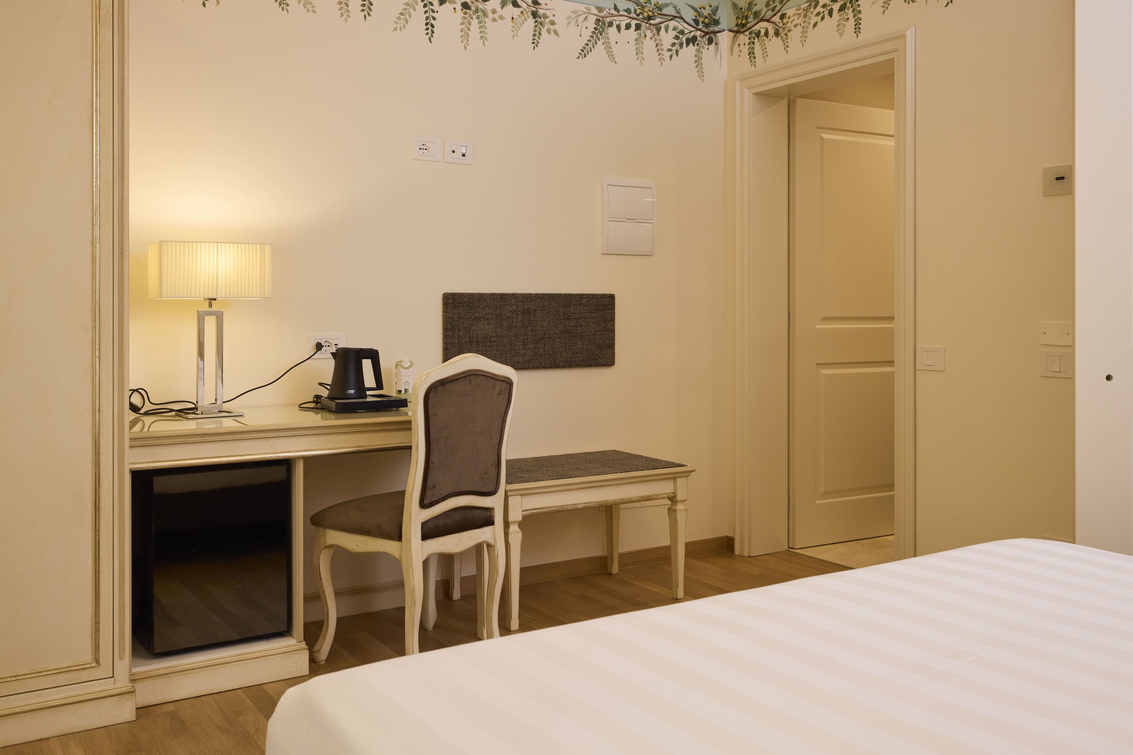 Habitación de hotel con una cama, un escritorio con lámpara, una silla y una mesita.