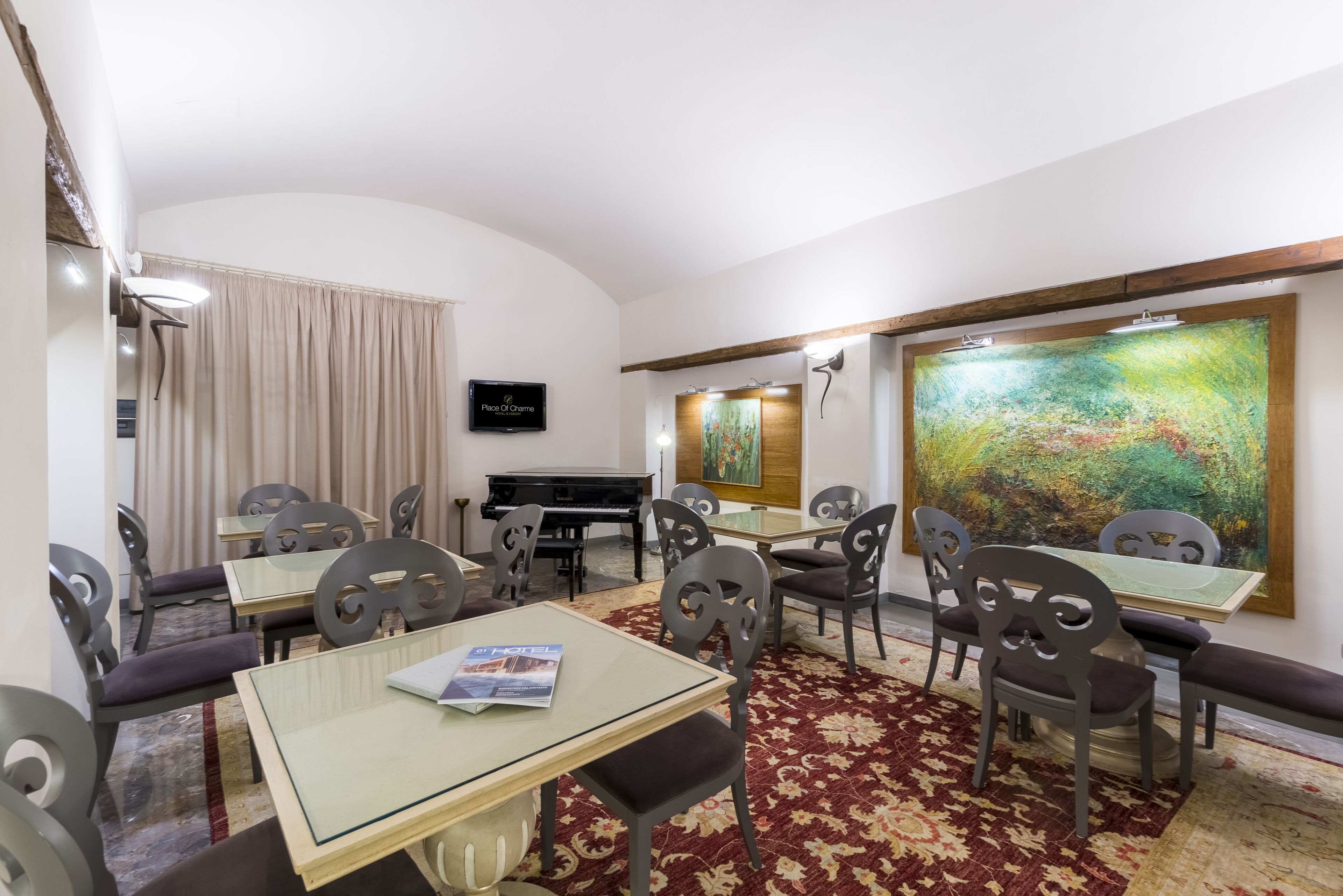 A hotel room with a dining area, a piano, and a large abstract painting.
