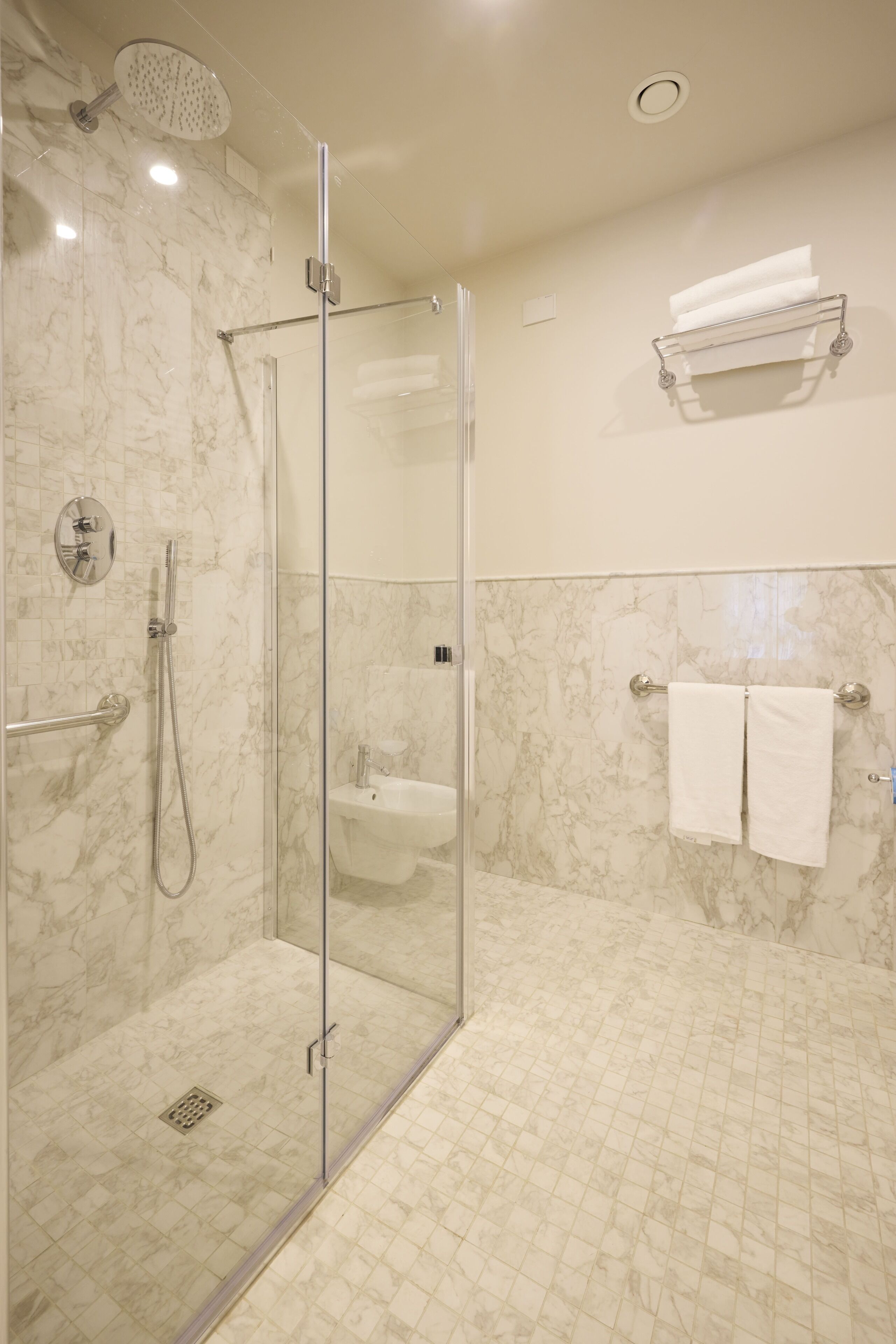 A modern bathroom with a glass-enclosed shower, a sink, and a towel rack.
