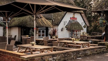 Sit and enjoy a drink at Fuller's outdoor seating area, featuring thatched-roof tables and wicker chairs.