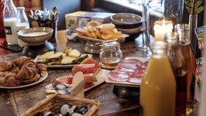 A table with various food items, including croissants, cheese, watermelon, and meat. There are also condiments and a candle in the background.