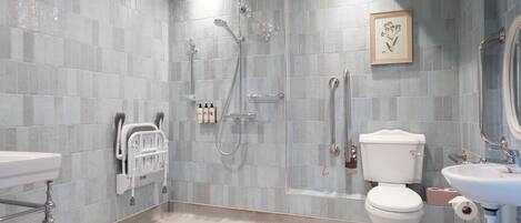 A modern bathroom with a shower, toilet, sink, and a framed picture on the wall.