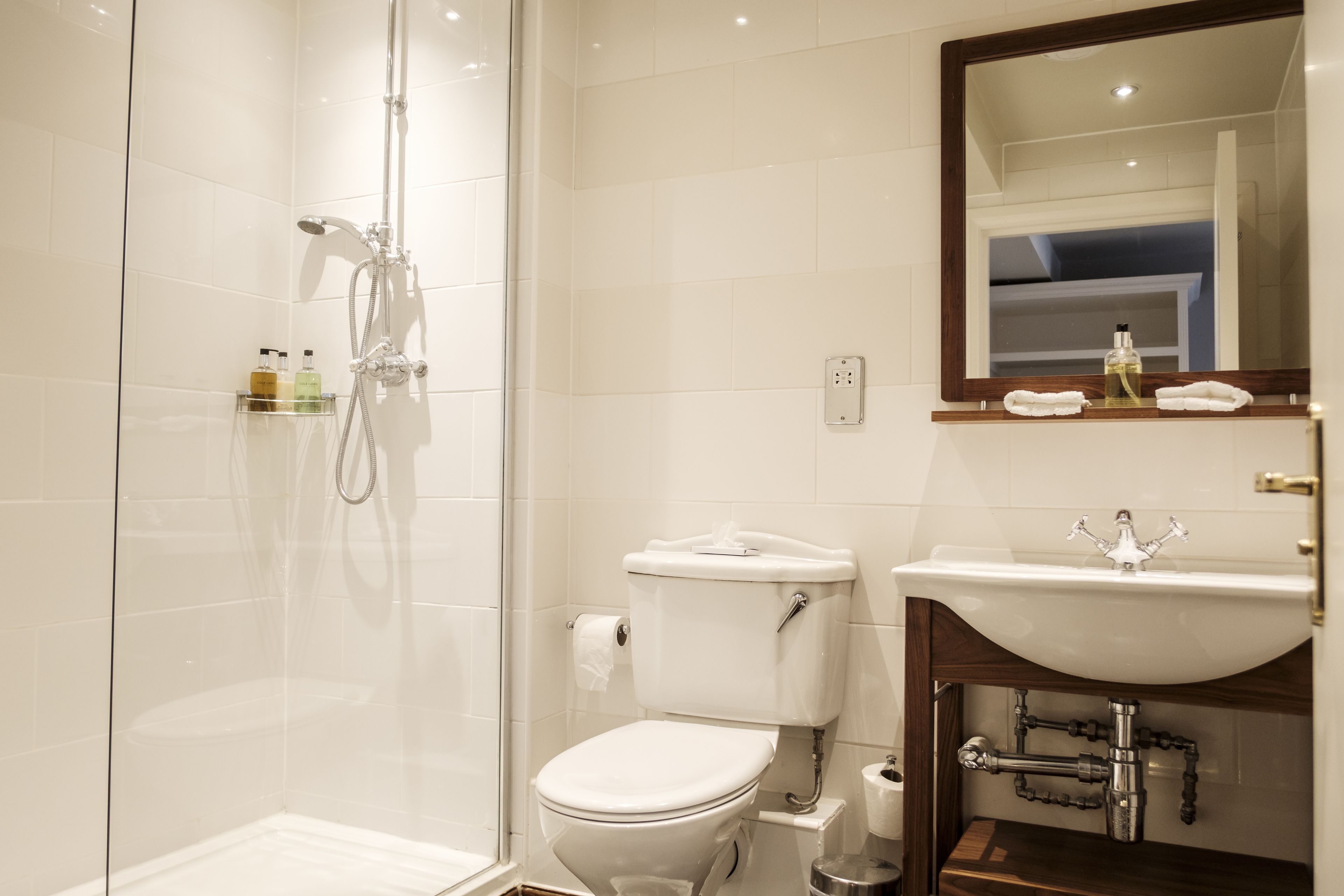 Een moderne badkamer met een douchecabine van glas, een wit toilet en een wastafel met spiegel erboven.