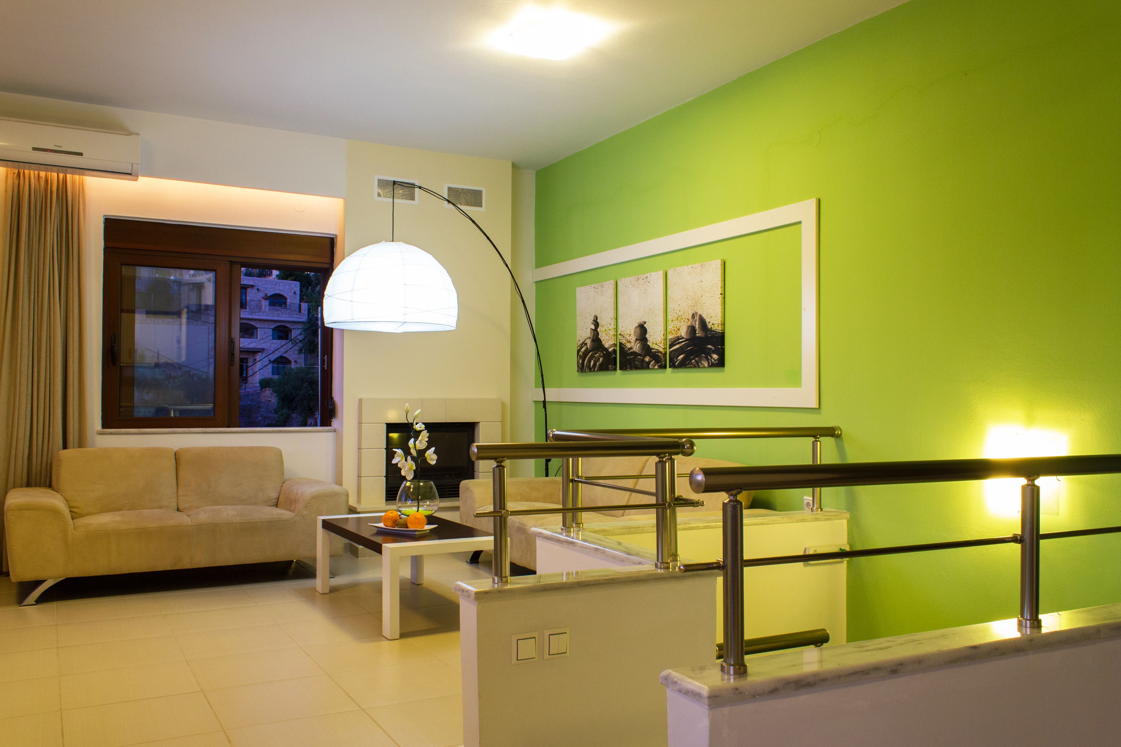 A living room with a sofa, coffee table, and artwork on a green wall.