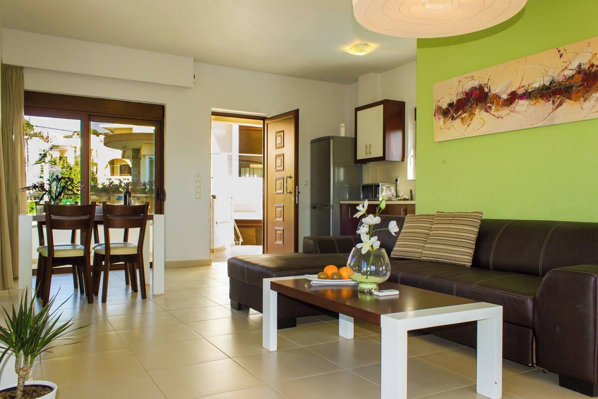 Una sala de estar moderna con un sofá, una mesa de comedor, sillas y una cocina al fondo.