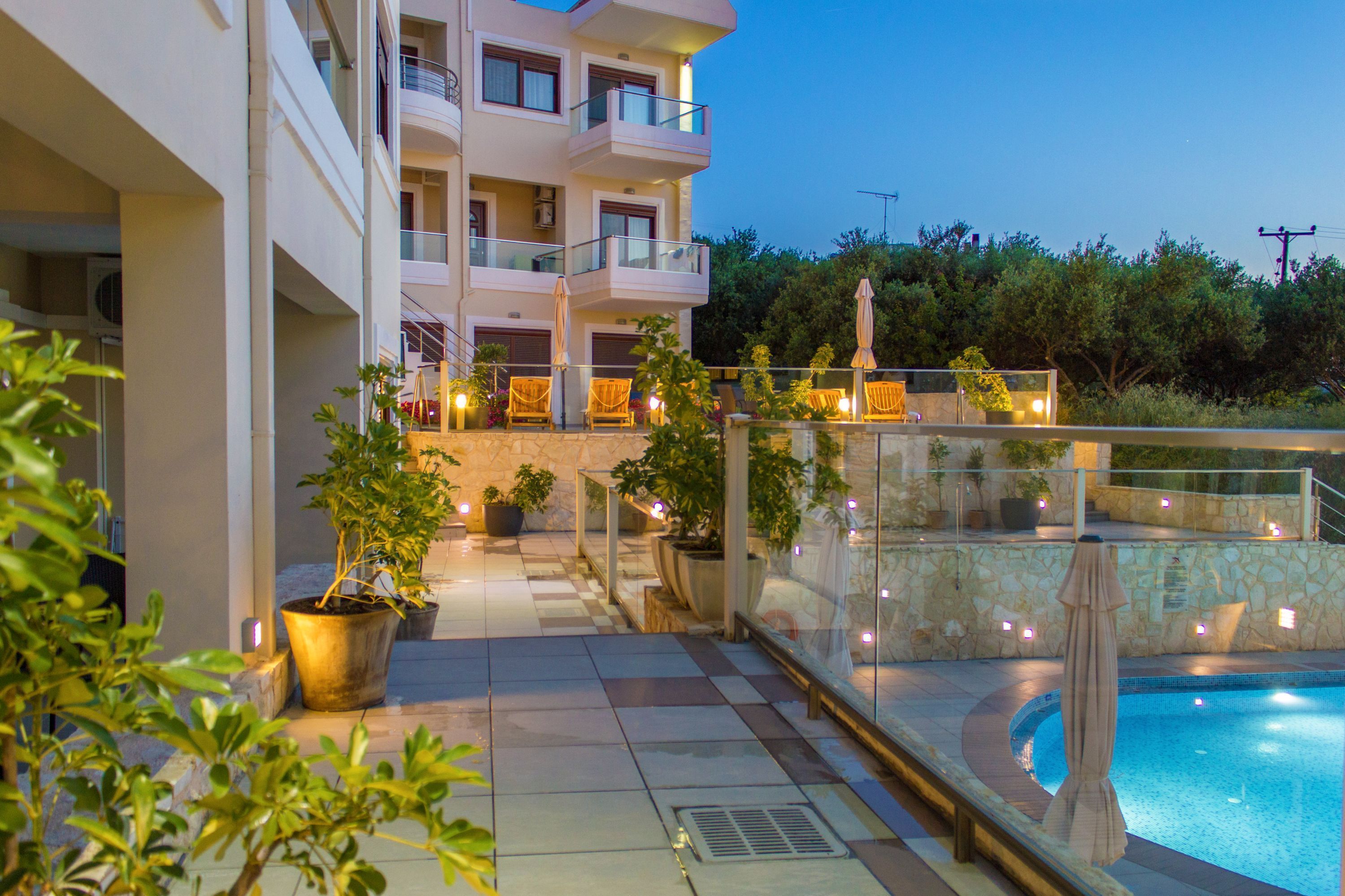Un hotel con piscina, mobiliario exterior y plantas en macetas.