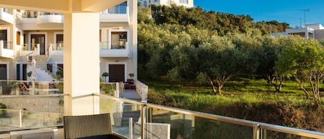 A modern apartment with a balcony overlooking a lush garden and a hillside.