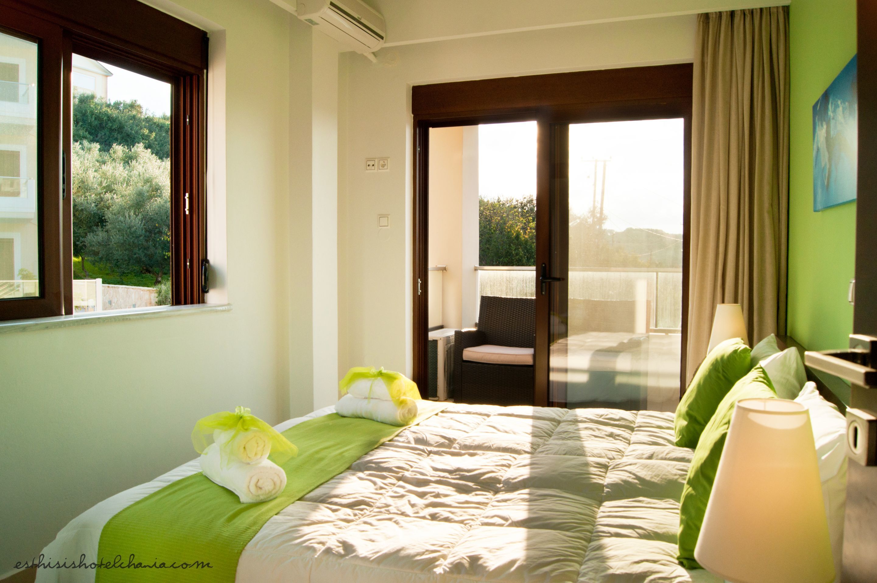 Habitación de hotel con cama, una silla, ventana y balcón.