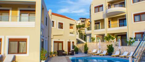 A hotel with a swimming pool, multiple balconies, and outdoor seating areas.