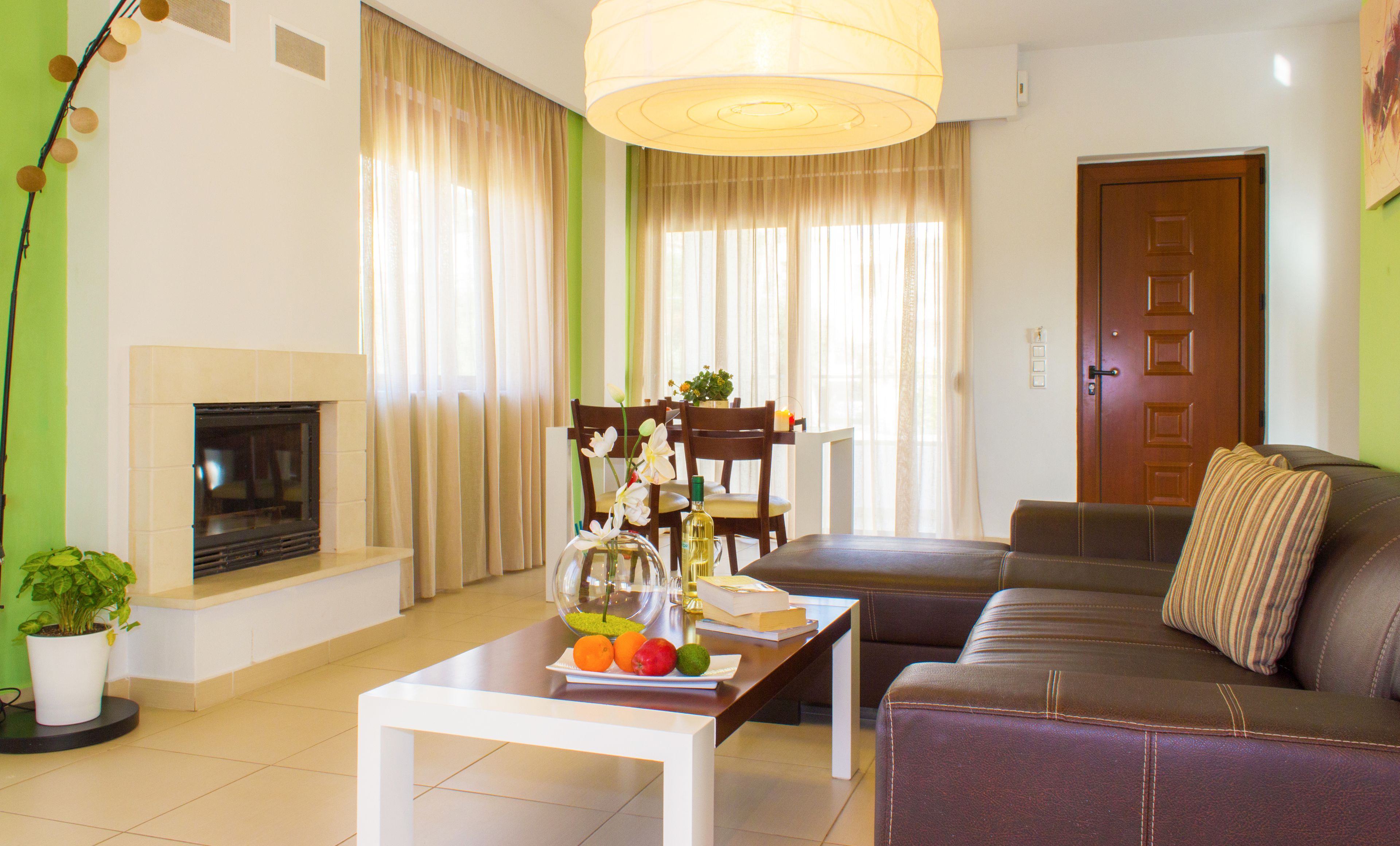 Ein Wohnzimmer mit Kamin, einer Couch, einem Couchtisch mit Früchten und einer Vase sowie einem Essbereich mit Stühlen und einem Tisch.