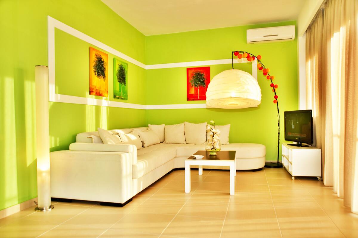 Una sala de estar con un sofá blanco, una mesa de centro y un mueble para la televisión.