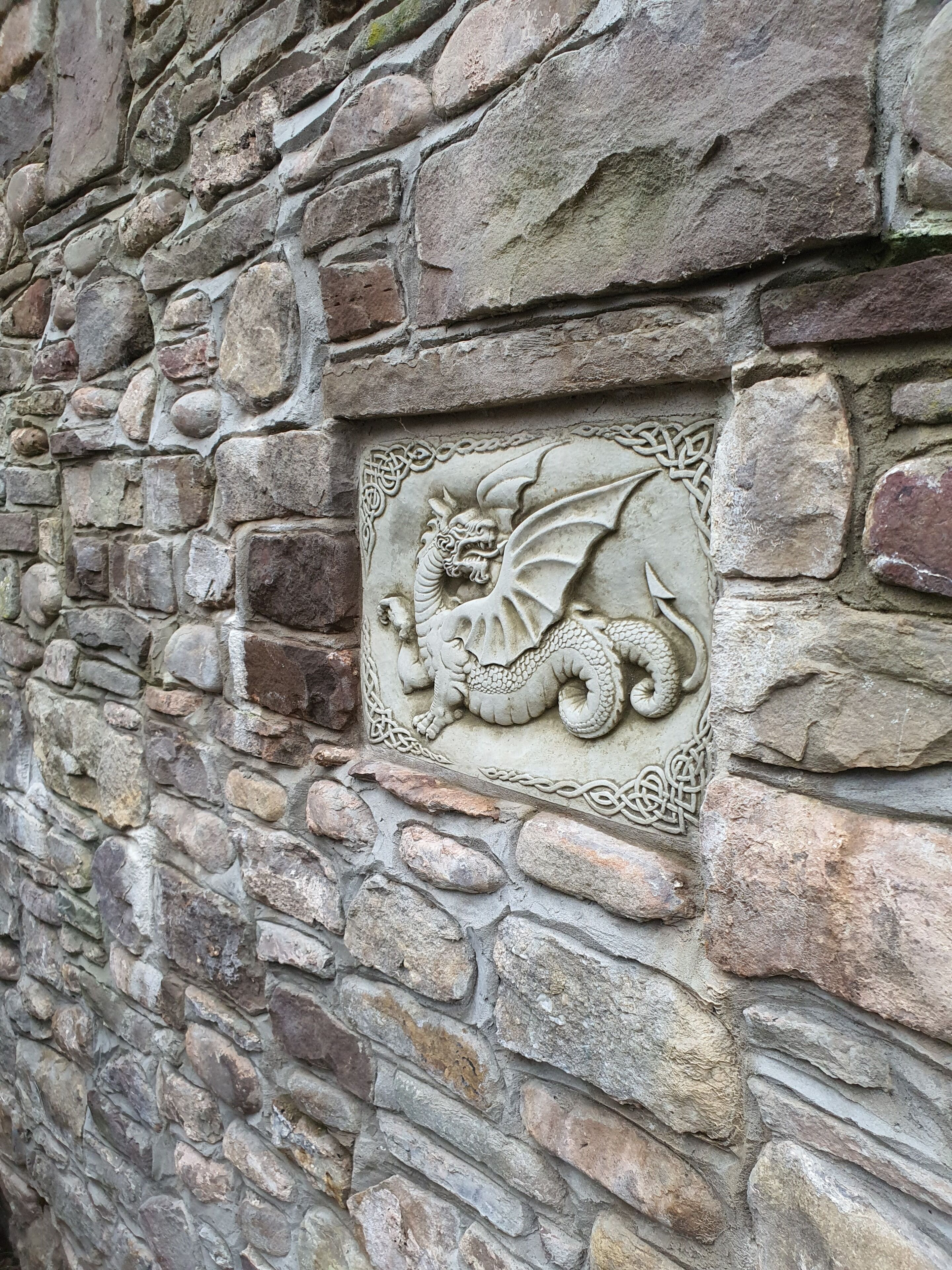 Un muro de piedra con un relieve de un dragón.