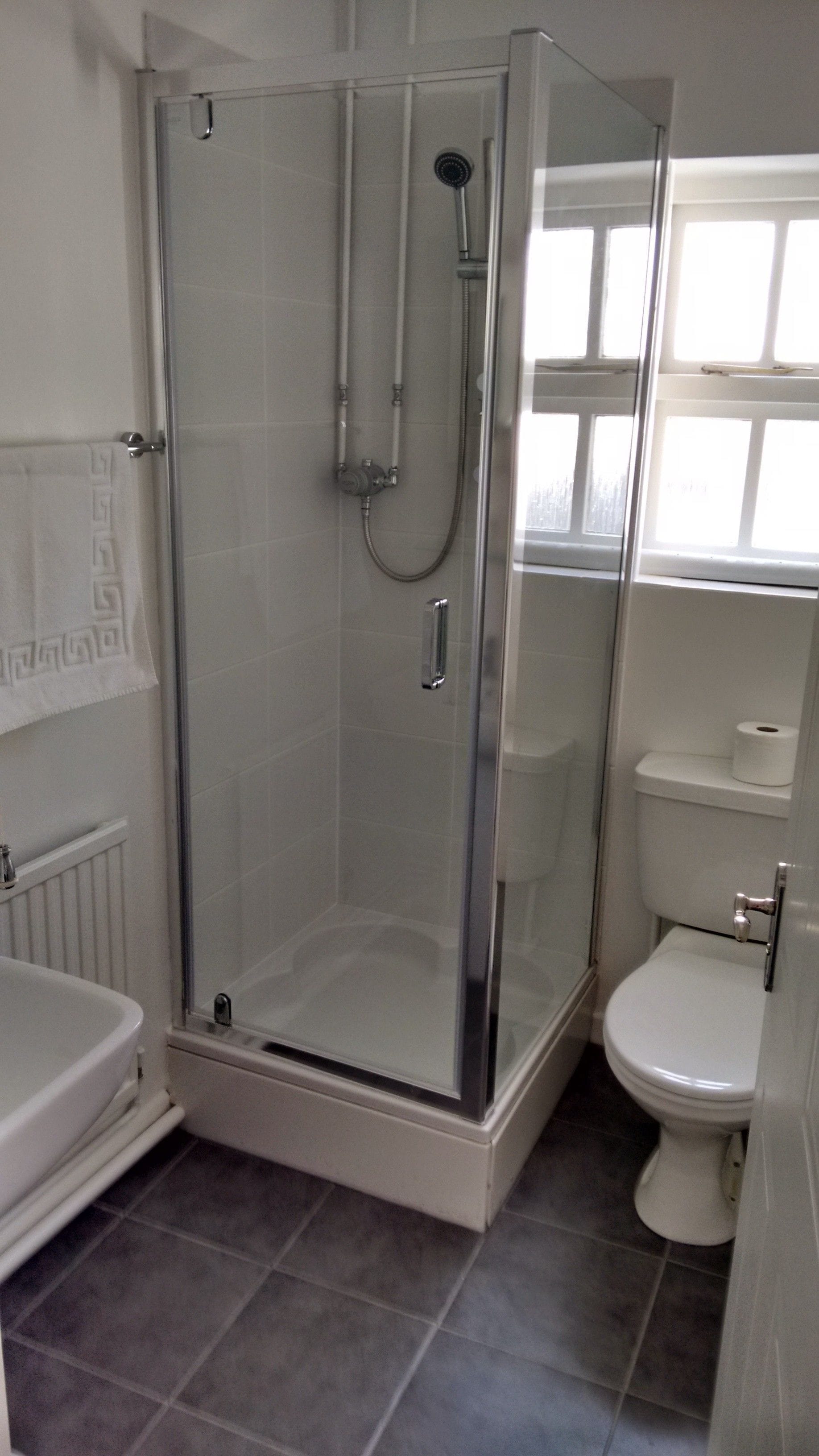 A bathroom with a glass-enclosed shower, a toilet, and a bathtub.