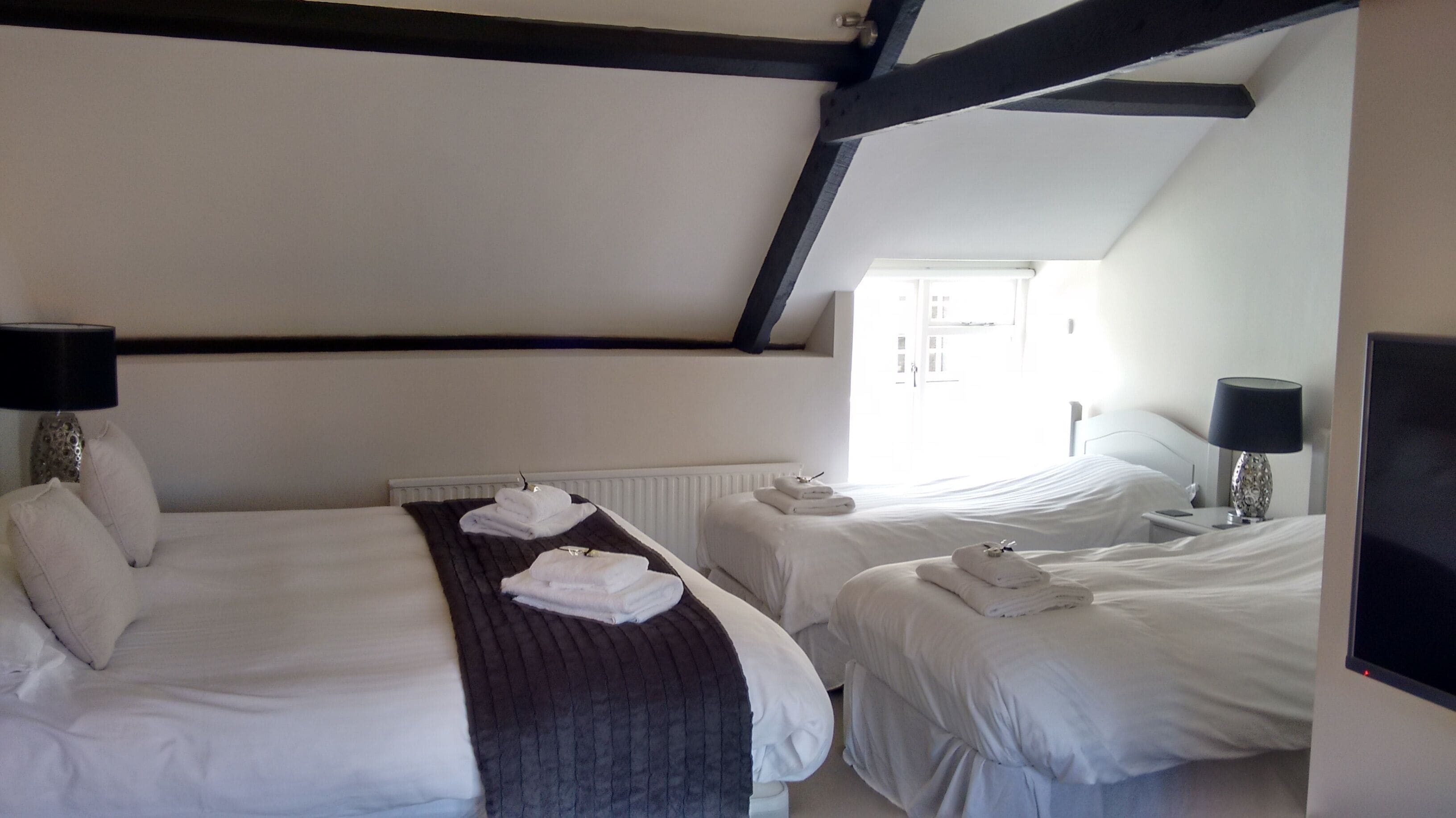 Una habitación de hotel con dos camas, un radiador, una ventana y un televisor.