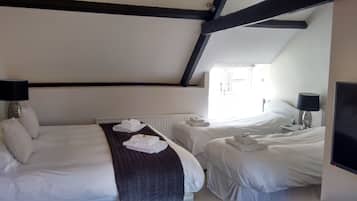 Una habitación de hotel con dos camas, un radiador, una ventana y un televisor.