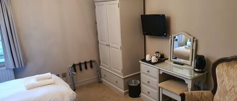 Une chambre d’hôtel avec deux lits, une armoire, un bureau avec un miroir, une chaise et un téléviseur.