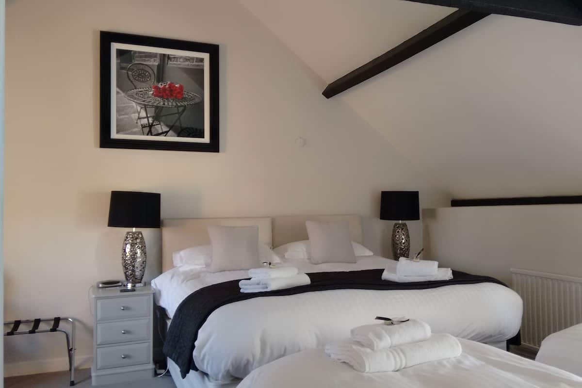 A neatly arranged bedroom with a bed, bedside lamps, a dresser, and a framed picture on the wall.