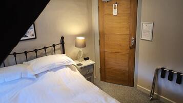 A hotel room with a bed, a nightstand, a lamp, a wooden door, and a wheelchair ramp.