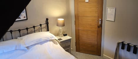 A hotel room with a bed, a nightstand, a lamp, a wooden door, and a wheelchair ramp.