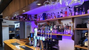 A bar area with multiple liquor bottles, a variety of taps, and a wooden counter.