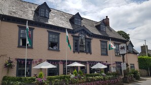 A traditional building with multiple flags, a sign for Dragon Inn, and outdoor seating with umbrellas.