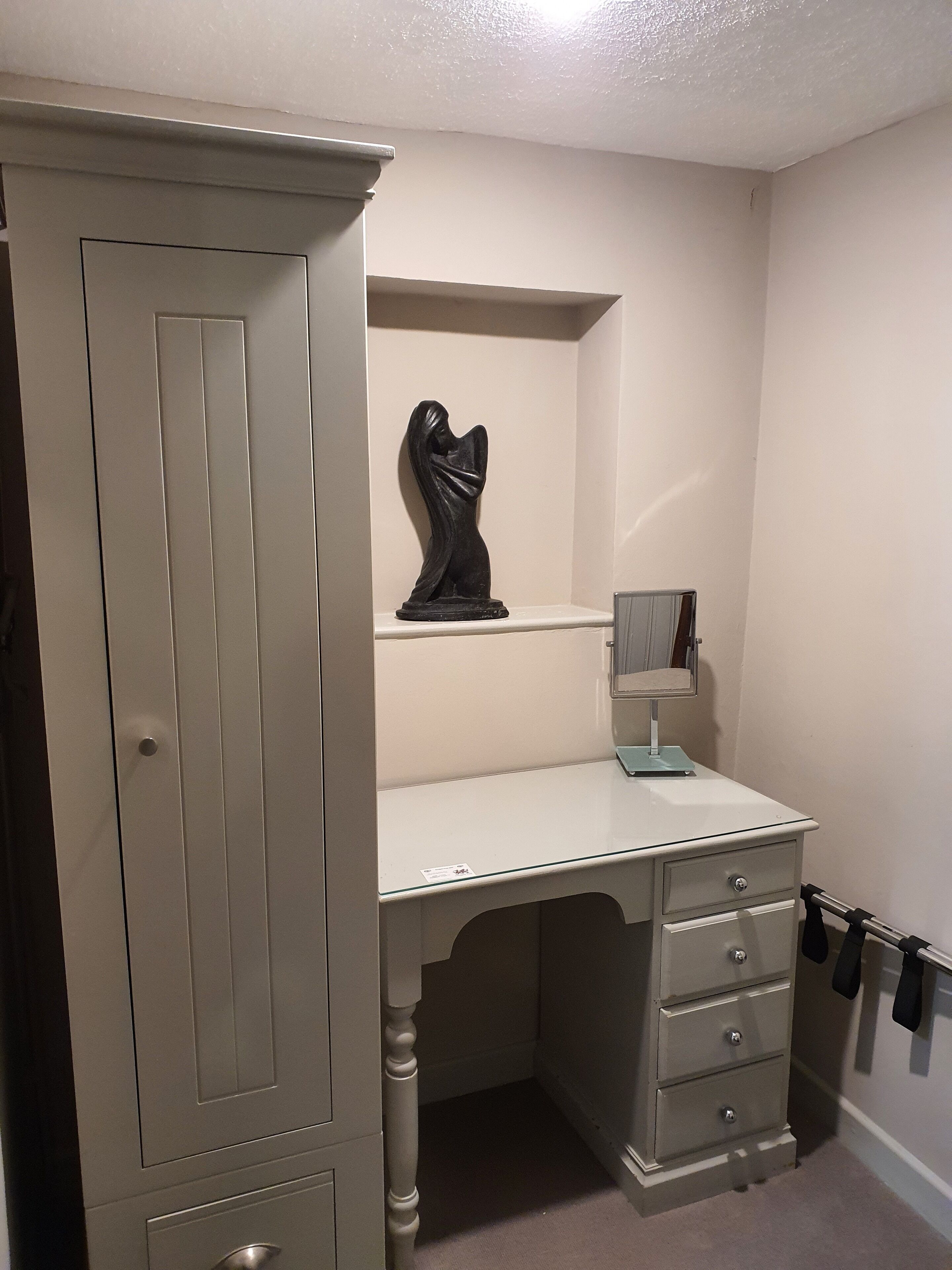 Un dormitorio con un armario, un escritorio y un espejo.