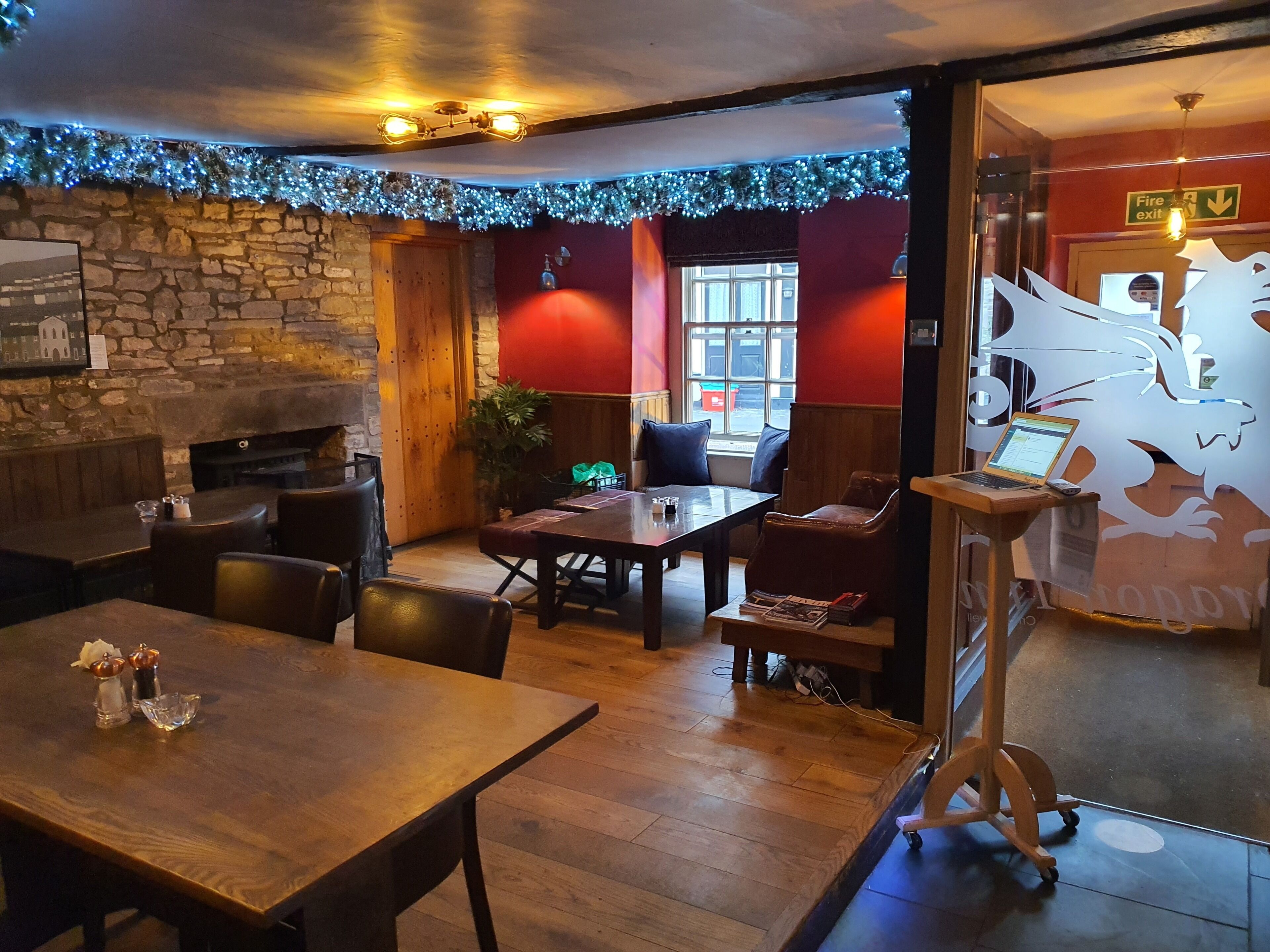 Un restaurante acogedor con mesas y sillas de madera, una pared de piedra y una chimenea.