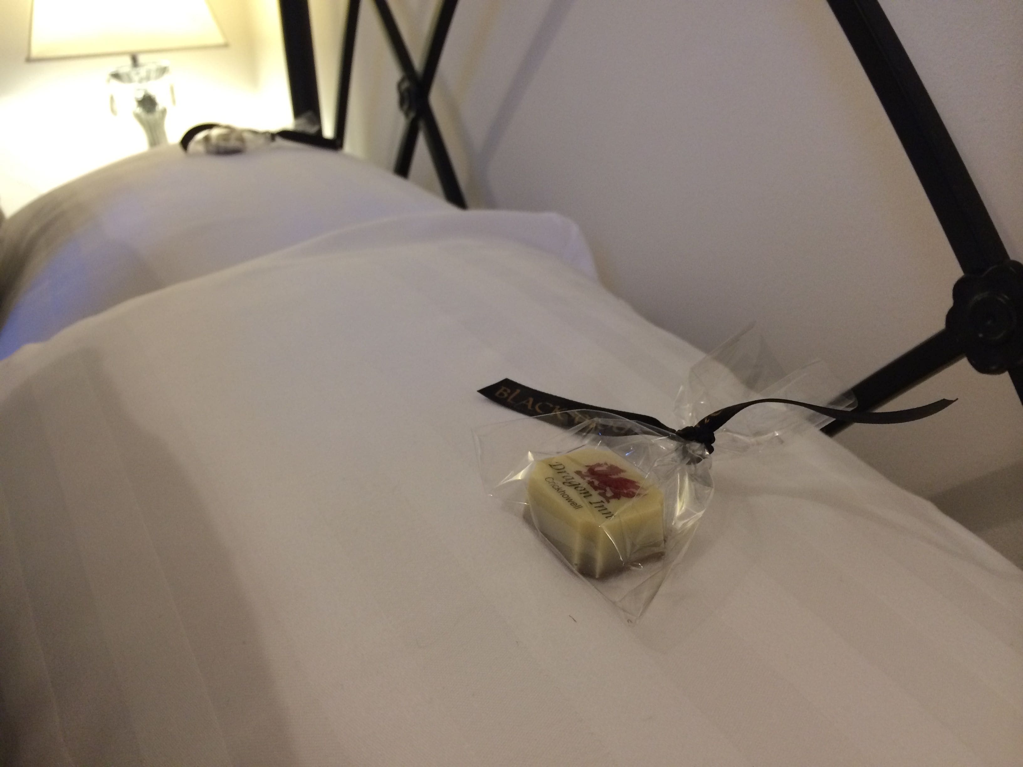 Una cama con un almohadón y un pequeño paquete de mantequilla encima.