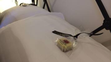 Una cama con un almohadón y un pequeño paquete de mantequilla encima.