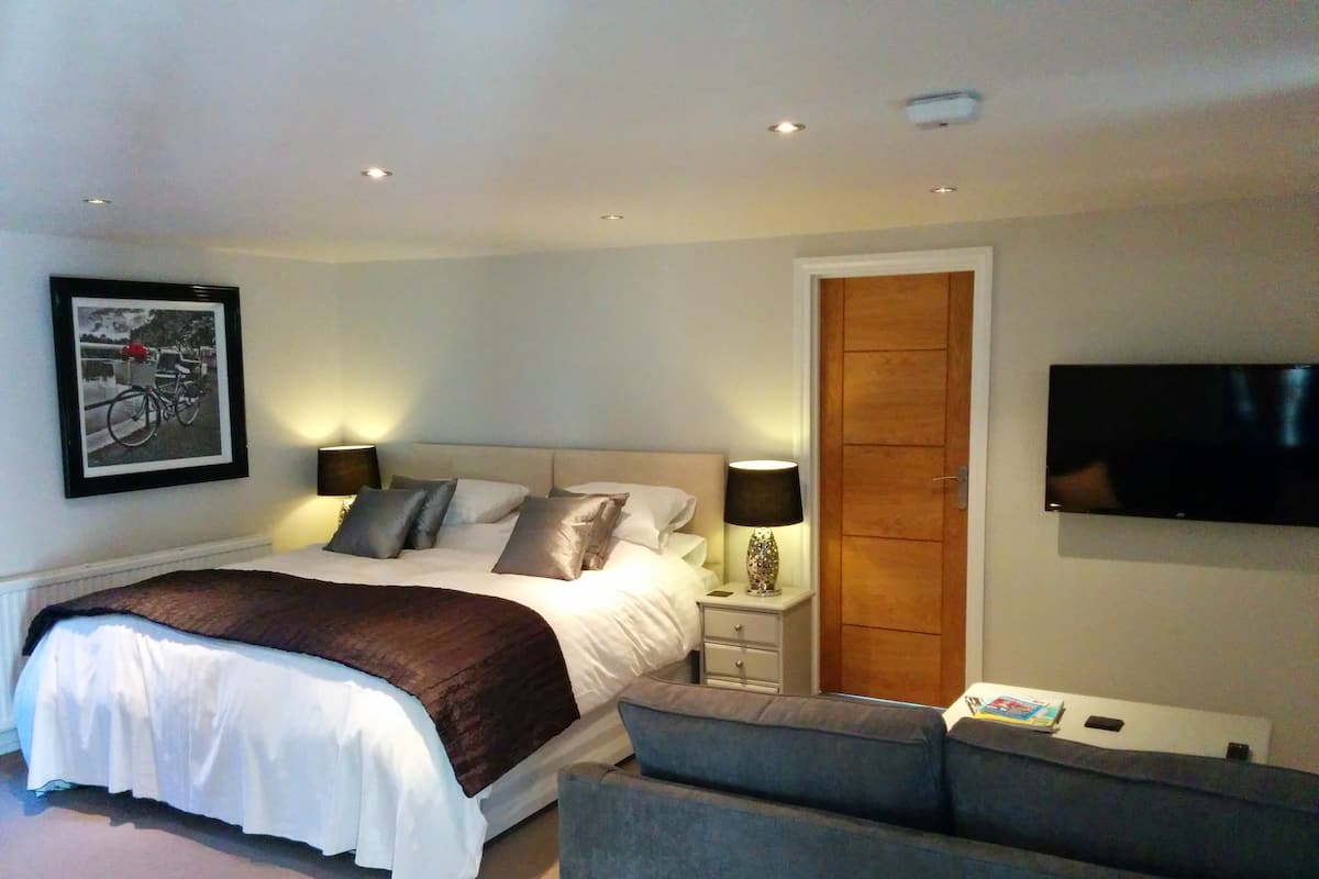 A bedroom with a bed, bedside tables, a TV, and a door.